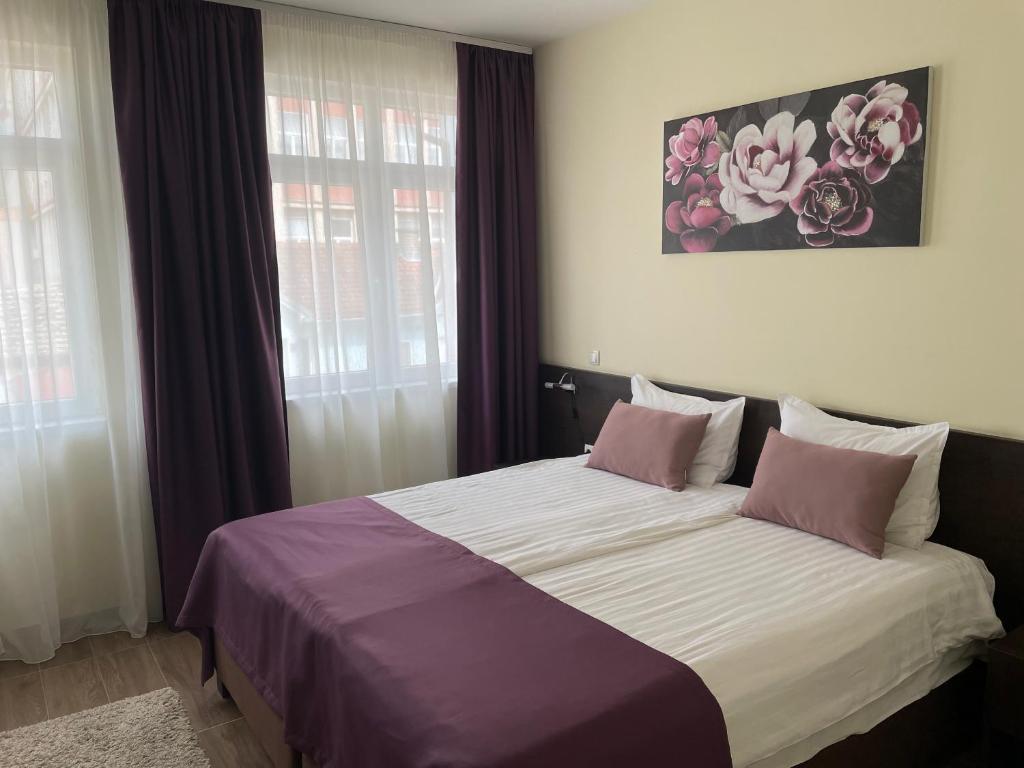 ein Schlafzimmer mit einem großen Bett mit lila und weißen Laken in der Unterkunft Santa Villa & restaurant in Sremska Mitrovica
