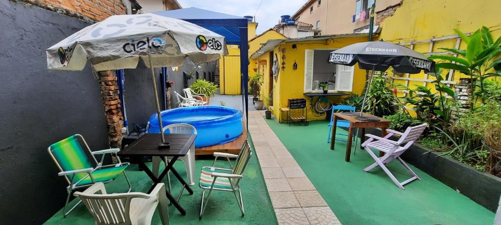 um pátio com uma mesa, cadeiras e um guarda-sol em Quintal da Bella Hostel em Santos