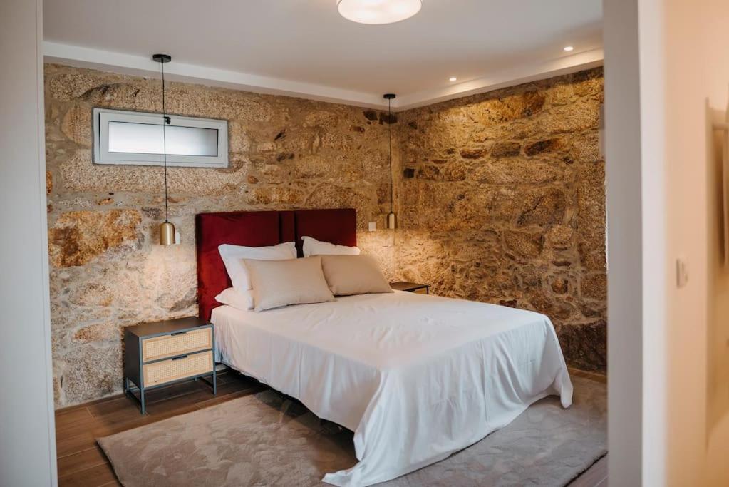 1 dormitorio con cama y pared de piedra en Sete Azenhas en Esposende