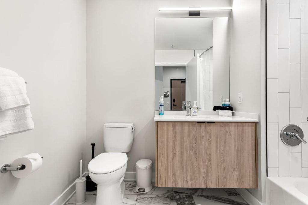 a bathroom with a toilet and a sink and a mirror at Avra Stylish Apartments Prime West Loop Location Near Union Park in Chicago