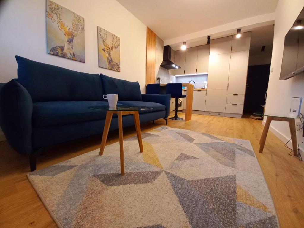 salon z niebieską kanapą i stołem w obiekcie NeoApartments Lotnicza we Wrocławiu