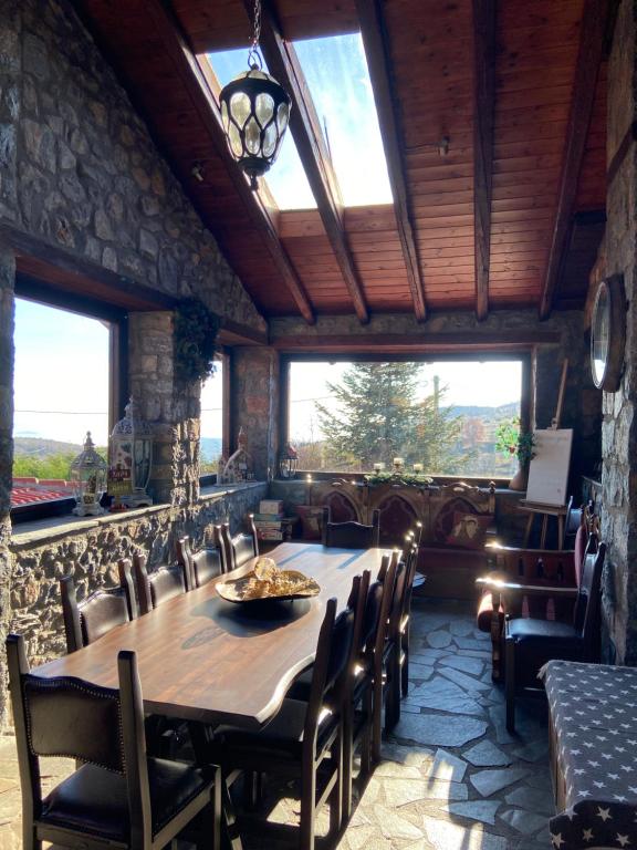 a dining room with a table and chairs and windows at Blessings Chalet στον Παλαιό Άγιο Αθανάσιο με Τζάκι, Barbeque, μεγάλη αυλή και υπέροχη θέα in Palaios Agios Athanasios