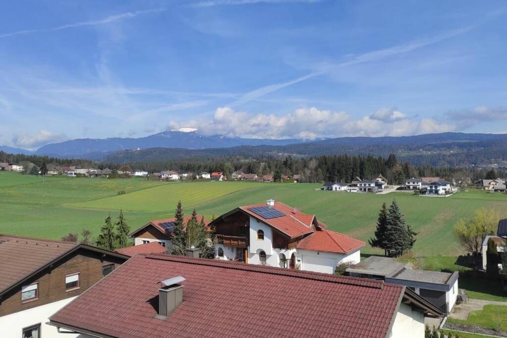 a house with a green field and mountains in the background at Appartement am Wörthersee in Selpritsch
