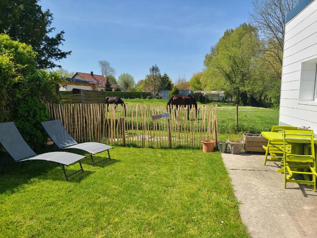 um quintal com cadeiras e uma cerca com cavalos ao fundo em Gîte Les amoureux de la Baie em Favières