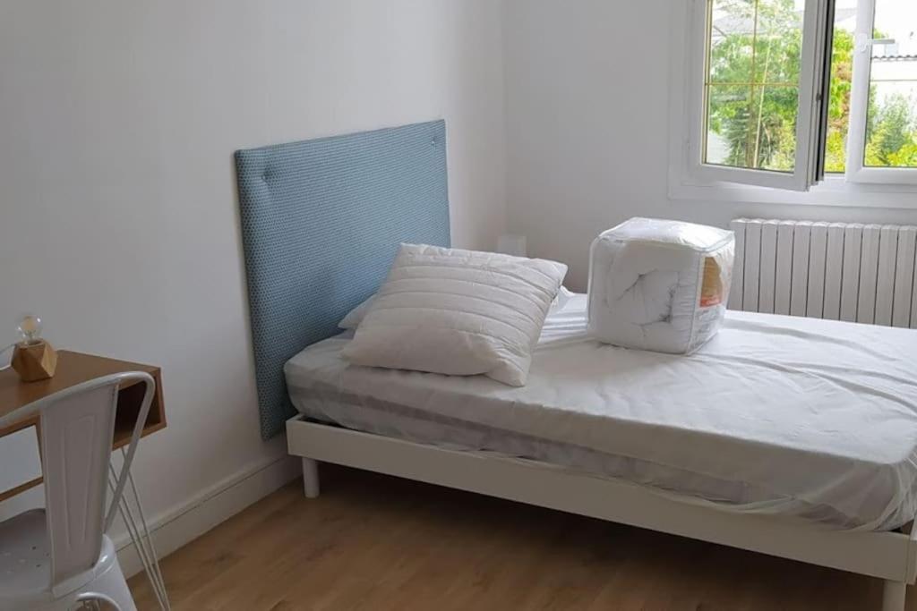 Bett mit weißer Bettwäsche und Kissen in einem Zimmer in der Unterkunft Maison 6 chambres avec jardin à Angers in Angers