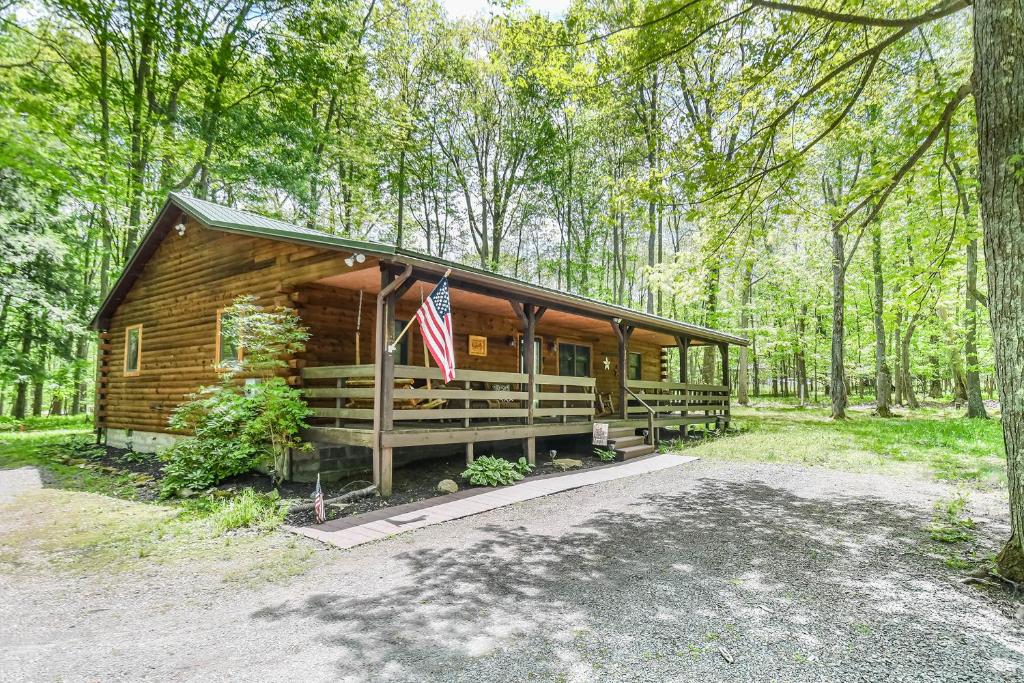 een blokhut in het bos met een Amerikaanse vlag bij Lincoln Log Cabin in Oakland