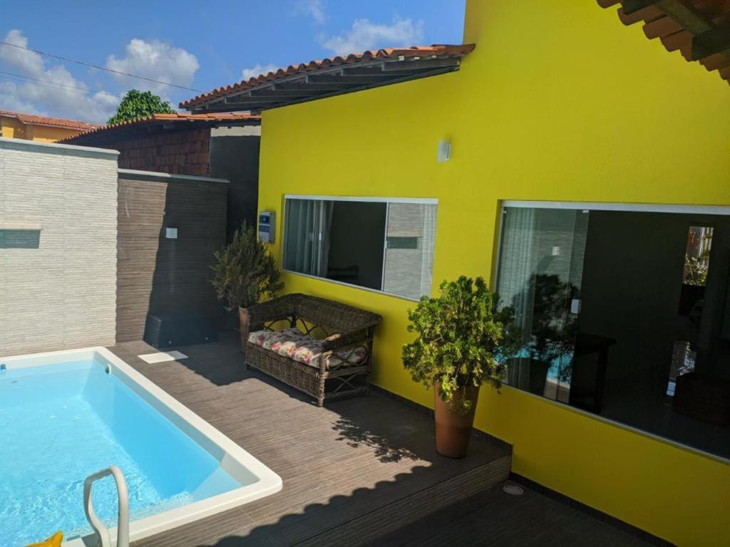 a backyard with a swimming pool and a yellow house at CASA TEMPORADA BARREIRINHAS 2 Quartos in Barreirinhas