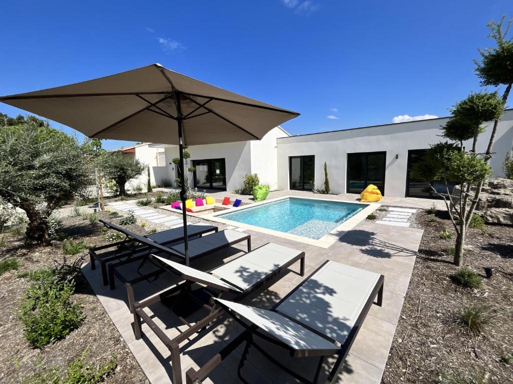 une terrasse avec un parasol et une piscine dans l'établissement Nirvana pop art piscine chauffé 4 chambres climatisées, à LʼIsle-sur-la-Sorgue