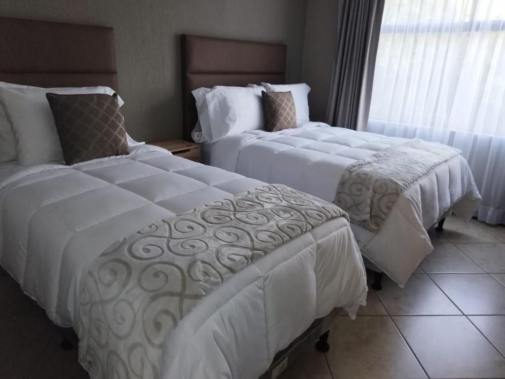 um quarto de hotel com duas camas e uma janela em L´Aurora Inn hostal em Guatemala