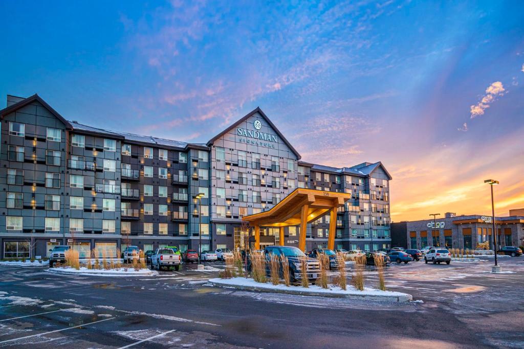 a large apartment building in a parking lot with a sunset at Sandman Signature Ottawa Airport Hotel in Ottawa