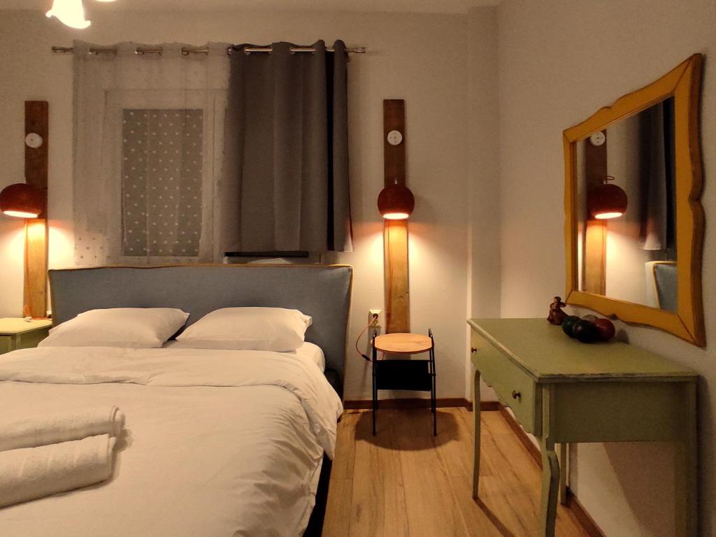 een slaapkamer met een bed, een bureau en een spiegel bij Kasoni Home , Απόλυτα κεντρικό διαμέρισμα μπροστά στη λίμνη in Kastoria