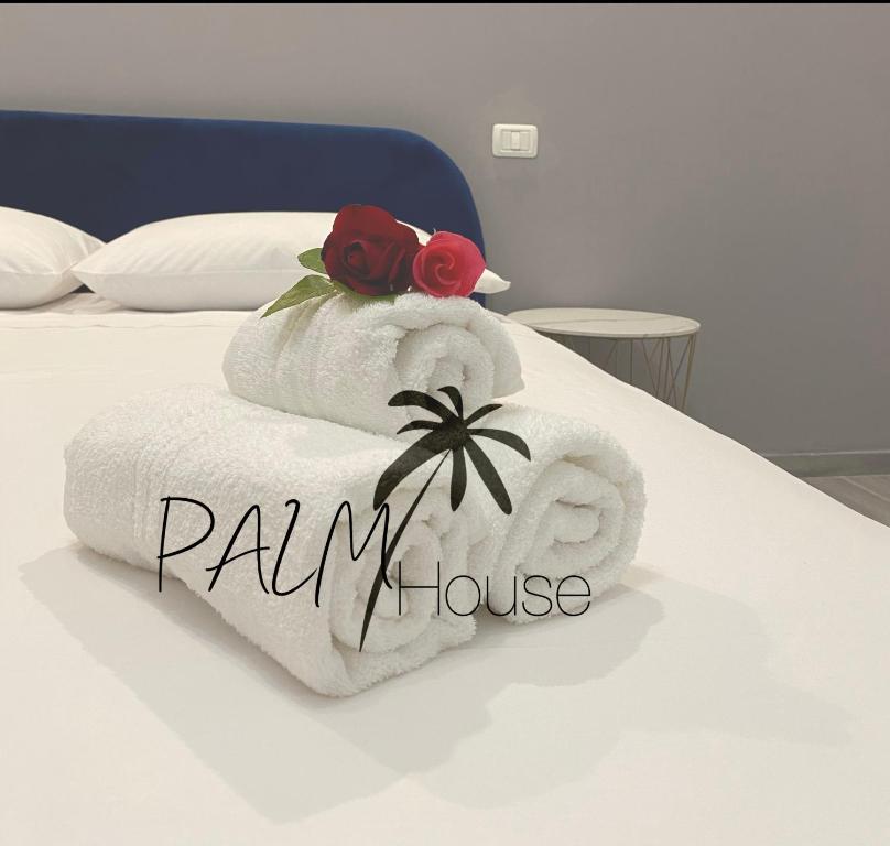 un mucchio di asciugamani seduti sopra un letto di PALM House Affitta camere a Tortolì
