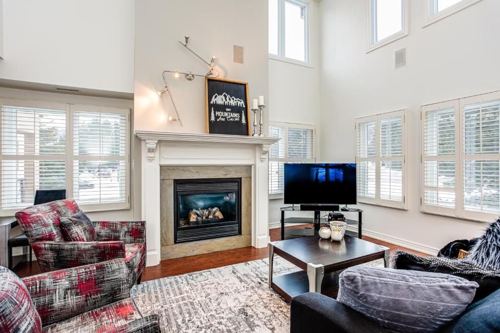 a living room with couches and a tv and a fireplace at 3 Bedroom Mountain Walk Condo, Steps to Village in Blue Mountains