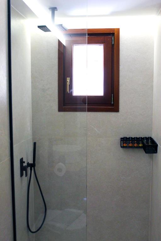 a bathroom with a glass shower with a window at Villa Almy in Plaka