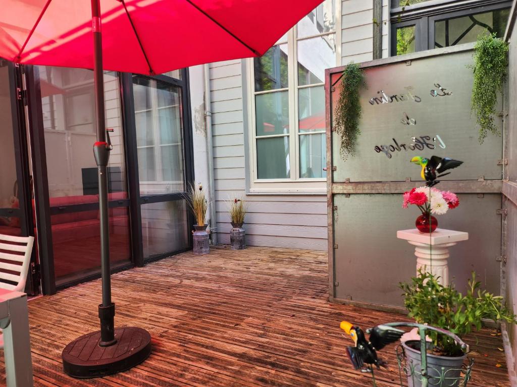 a house with a red umbrella on a patio at Le jardin de l&#39;horloge in La Rochelle