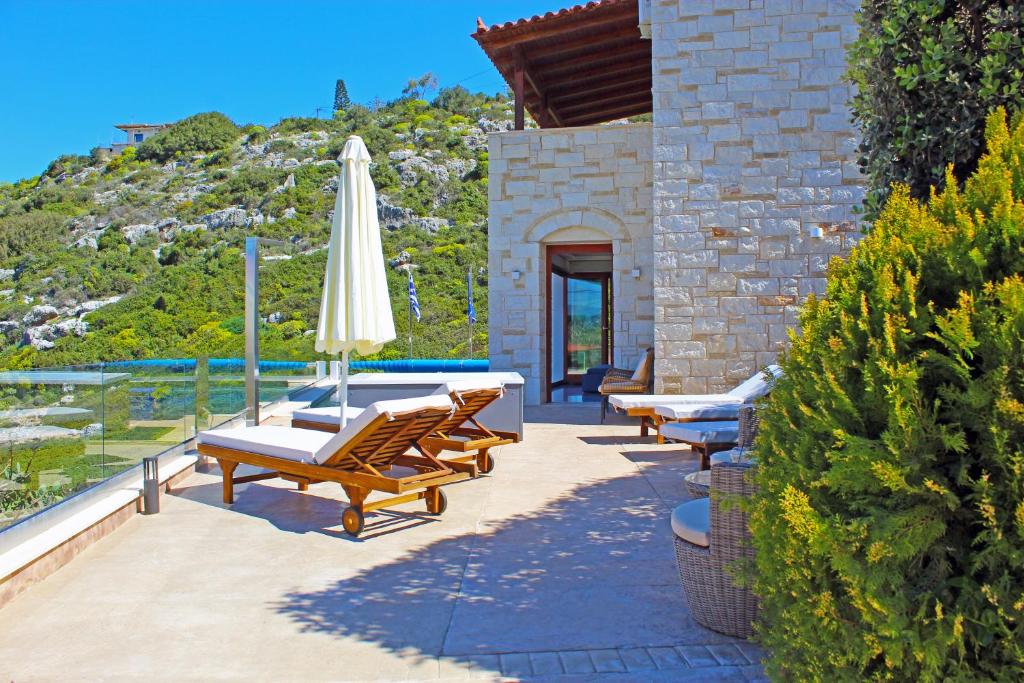 a patio with tables and chairs and an umbrella at Villa Almy in Plaka