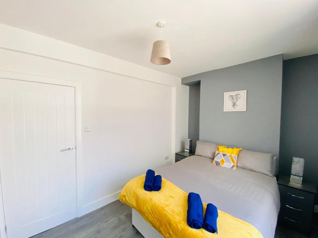 a bedroom with a bed with blue cushions on it at Emerald Properties UK 4 bedrooms - Swansea City Centre, close to beaches! in Swansea