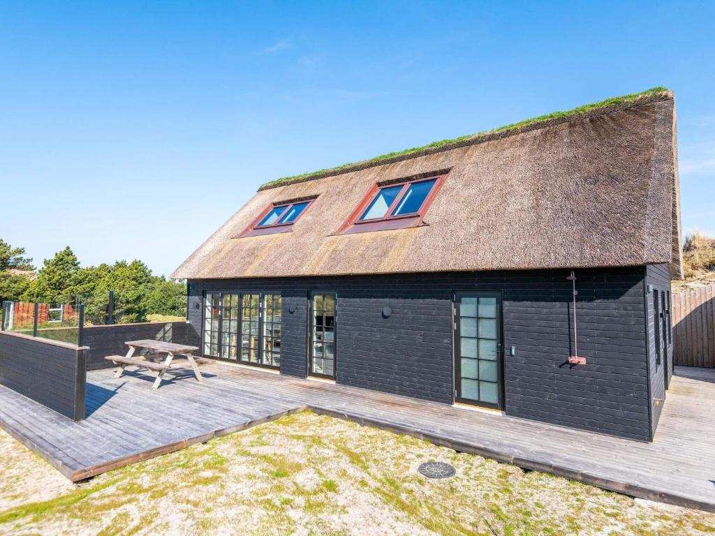een zwart huis met een dak en een patio bij Holiday home Fanø XIV in Fanø