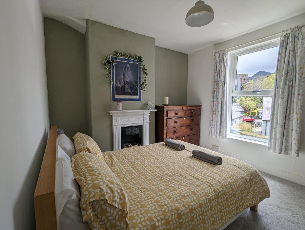 a bedroom with a bed and a fireplace and a window at Perfect for Snowdon. Groups, families+dogs welcome in Llanberis