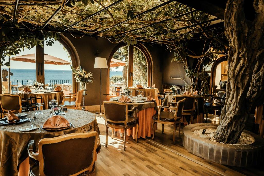 a restaurant with tables and chairs and a tree at Rigat Park & Spa Hotel - Adults Recommended in Lloret de Mar
