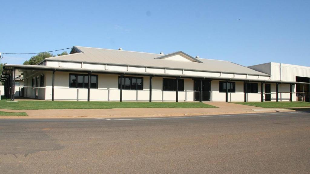 a white building with black windows on a street at Burketown Pub in Burketown
