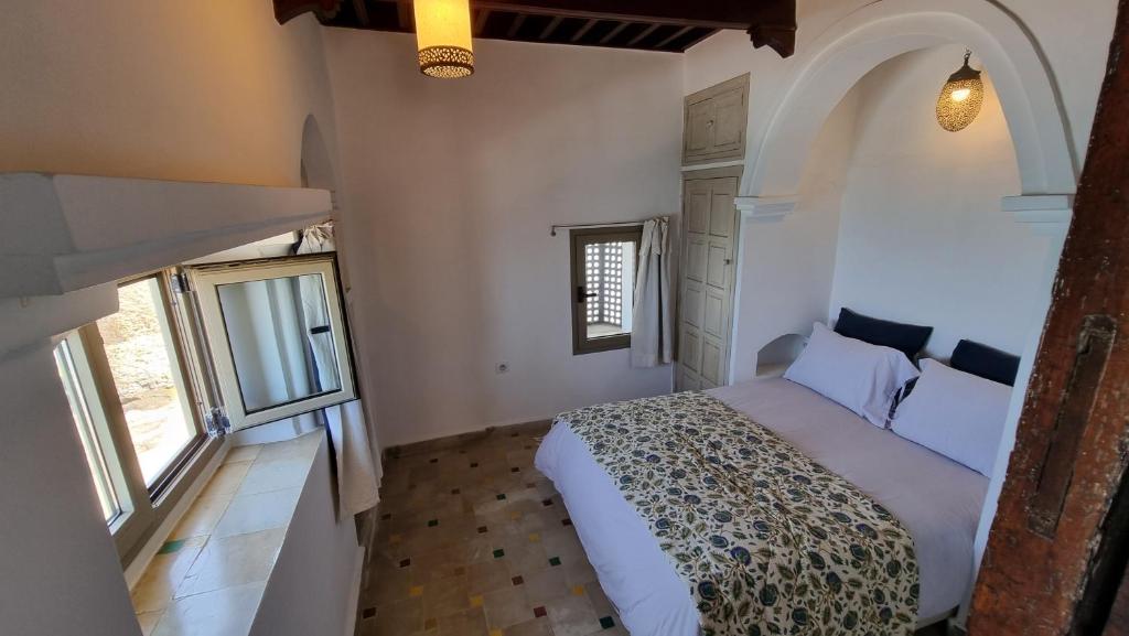 um quarto com uma cama num quarto com janelas em Chambre bord de mer em Arzila