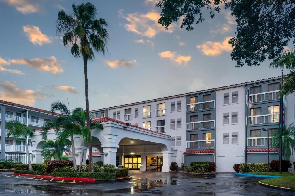 un edificio con una palmera delante de él en Holiday Inn & Suites Boca Raton - North, en Boca Raton