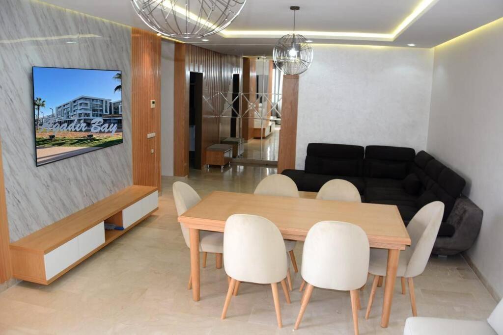 AGADIR BAY Appartement de haut standing 140m2 في أغادير: غرفة معيشة مع طاولة طعام وأريكة