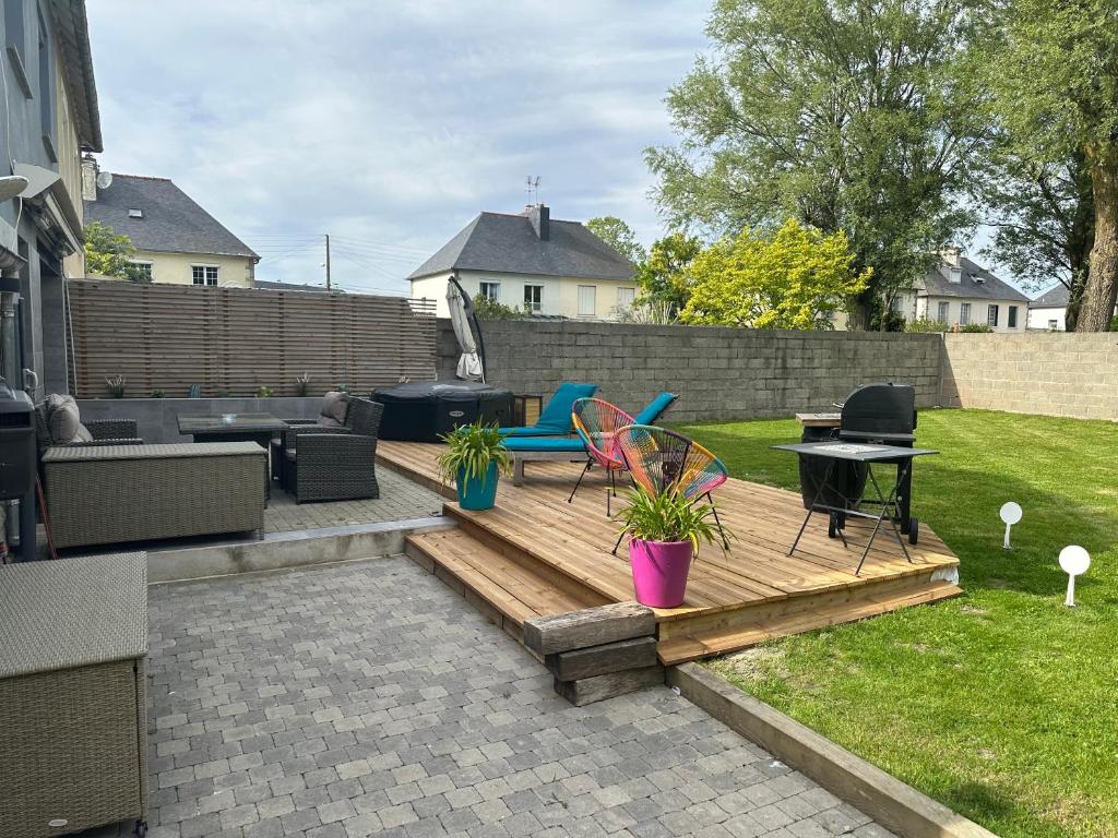 un patio trasero con una terraza de madera con sillas y una mesa en Maison toute équipée 3 chambres avec jardin calme et Spa, en Saint-Malo