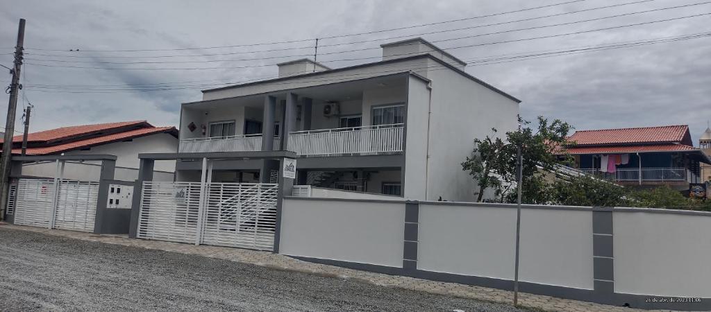 ein weißes Haus mit einem Zaun davor in der Unterkunft Apart ZSS in Penha