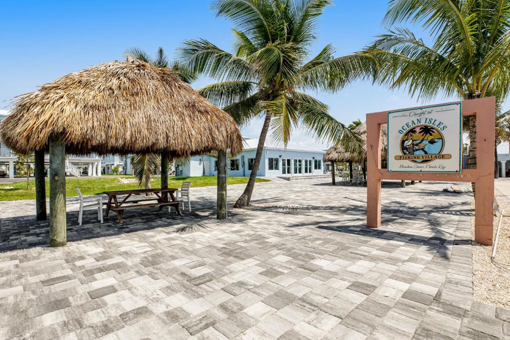 a sign on a beach with palm trees and a building at Keys to Happiness in Marathon
