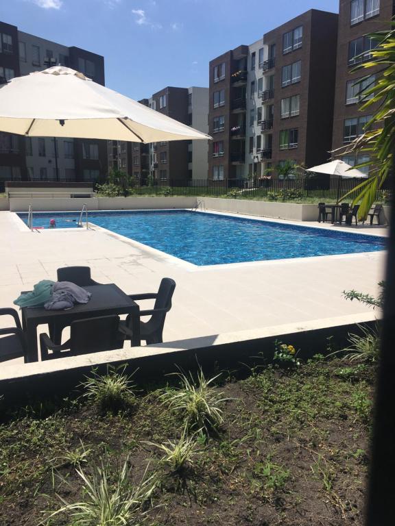 una piscina con tavolo e due sedie e ombrellone di Apartamento villavicencio a Villavicencio