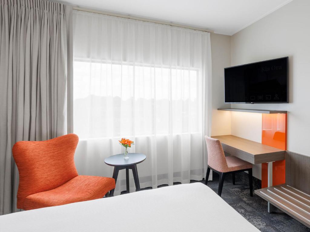 a hotel room with a bed and a desk and chairs at JetPark Auckland Airport Hotel in Auckland
