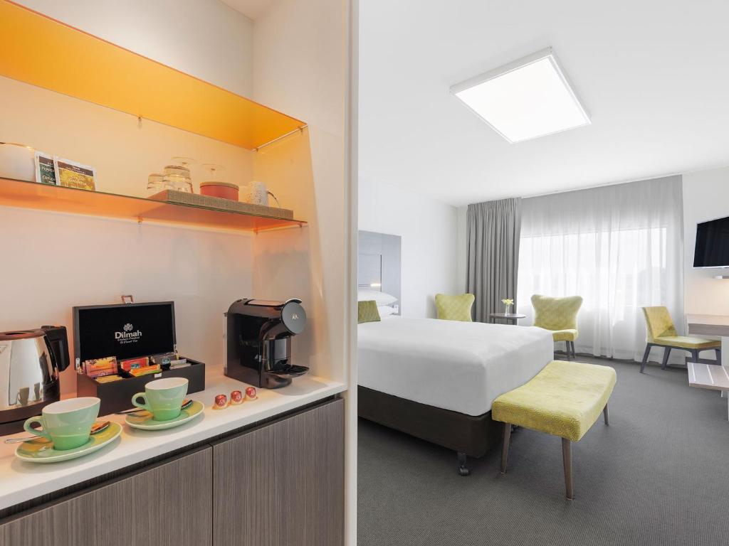 a hotel room with a bed and a desk with a microwave at JetPark Auckland Airport Hotel in Auckland