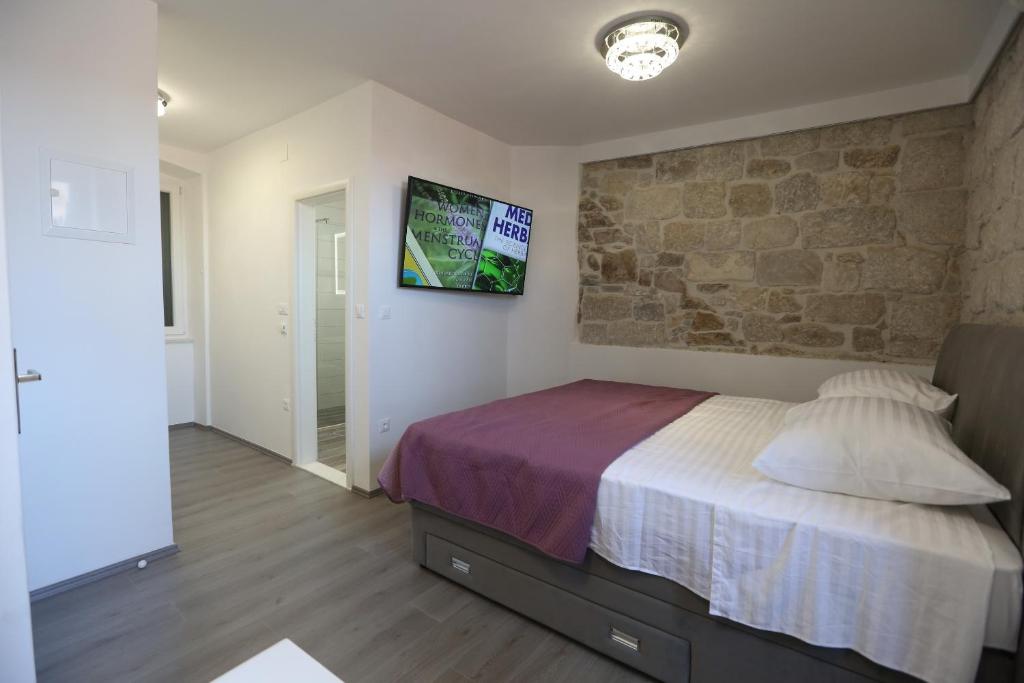 1 dormitorio con cama y pared de piedra en Villa Kate, en Split