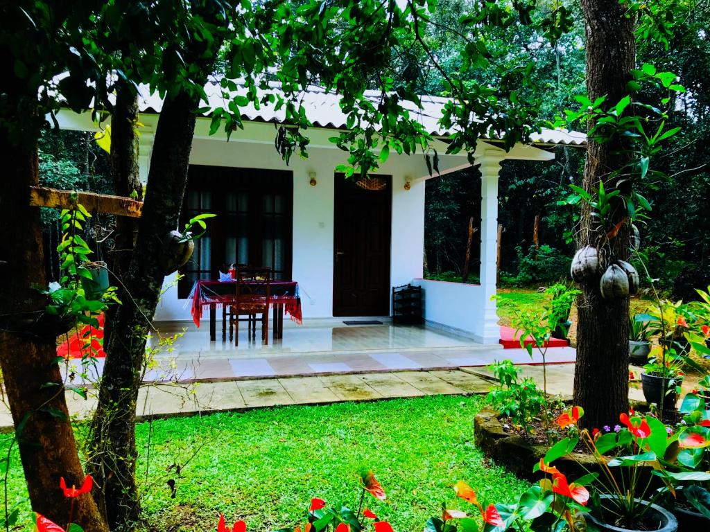 una casa con giardino e tavolo con fiori rossi di Holly Flowers Villa a Sigiriya
