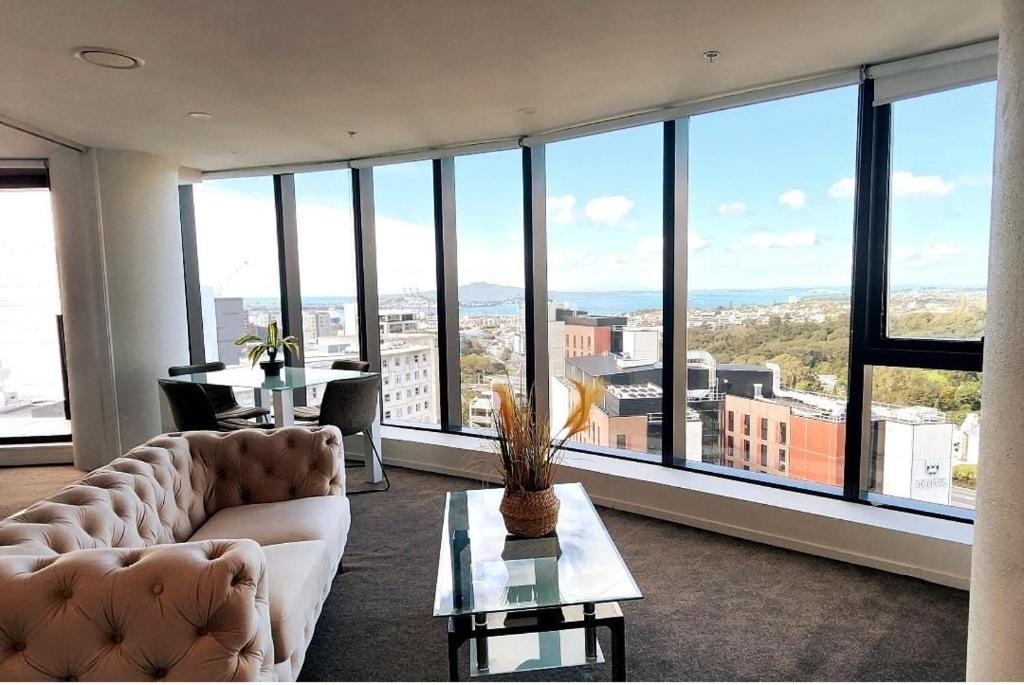 a living room with a couch and tables and large windows at Pinnacle Apartment in Auckland