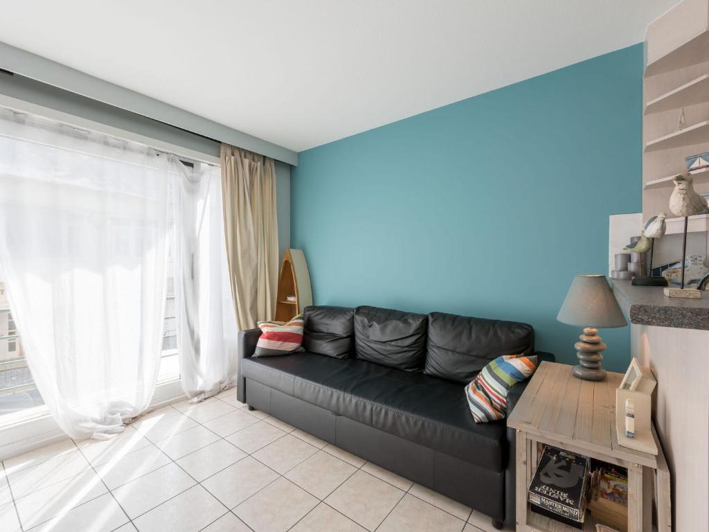 een woonkamer met een zwarte bank en een blauwe muur bij Apartment in Koksijde near the Sea in Koksijde