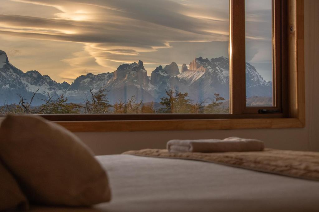 1 dormitorio con ventana y vistas a la montaña en Pampa Lodge, Quincho & Caballos, en Torres del Paine