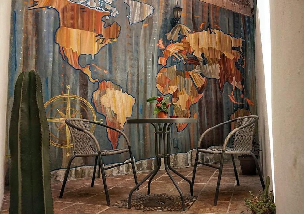 a table and chairs in front of a world mural at El rincón de la Escandón in Mexico City