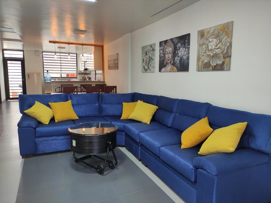 バーニョスにあるElegante apartamento con vistas al volcán Tungurahuaの青いソファ(黄色の枕付)が備わるリビングルーム