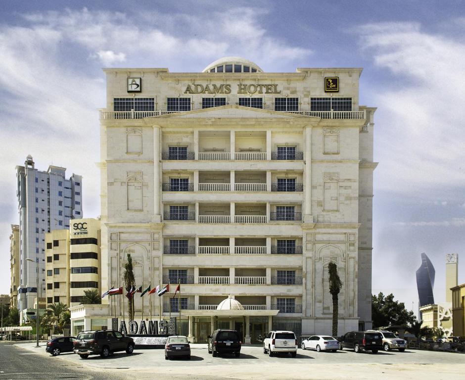 un gran edificio con coches estacionados en un estacionamiento en Adams Hotel en Kuwait