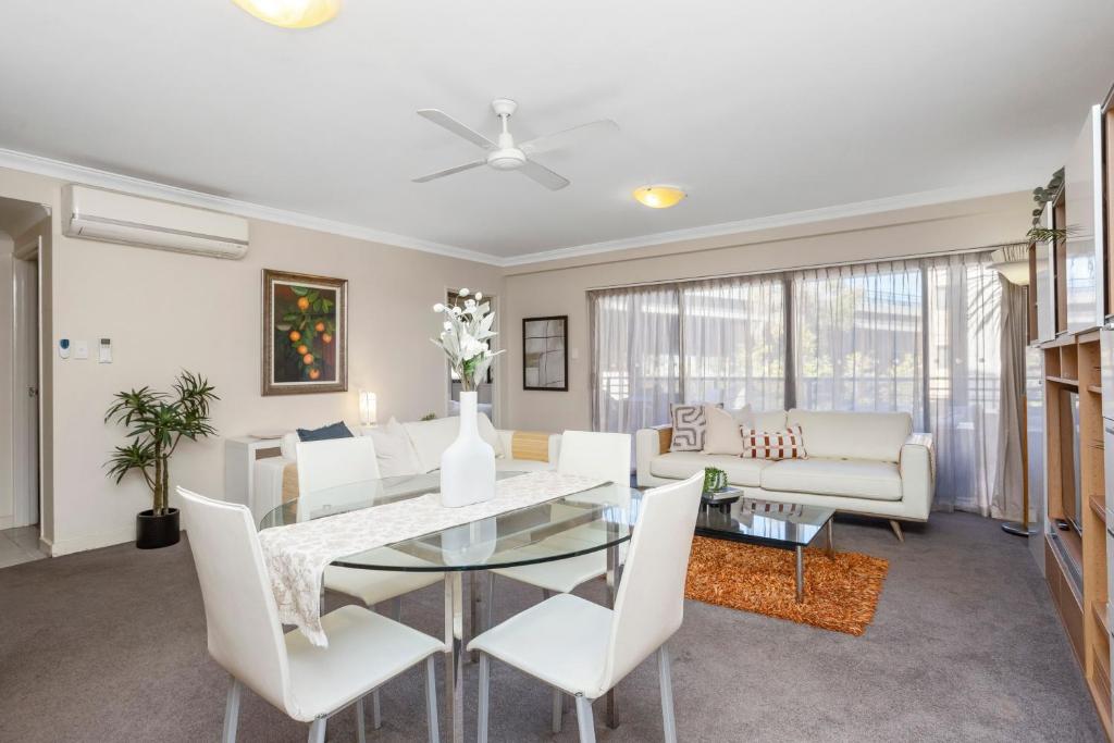 een woonkamer met een glazen tafel en witte stoelen bij Executive 2br Suite On Mounts Bay Road in Perth