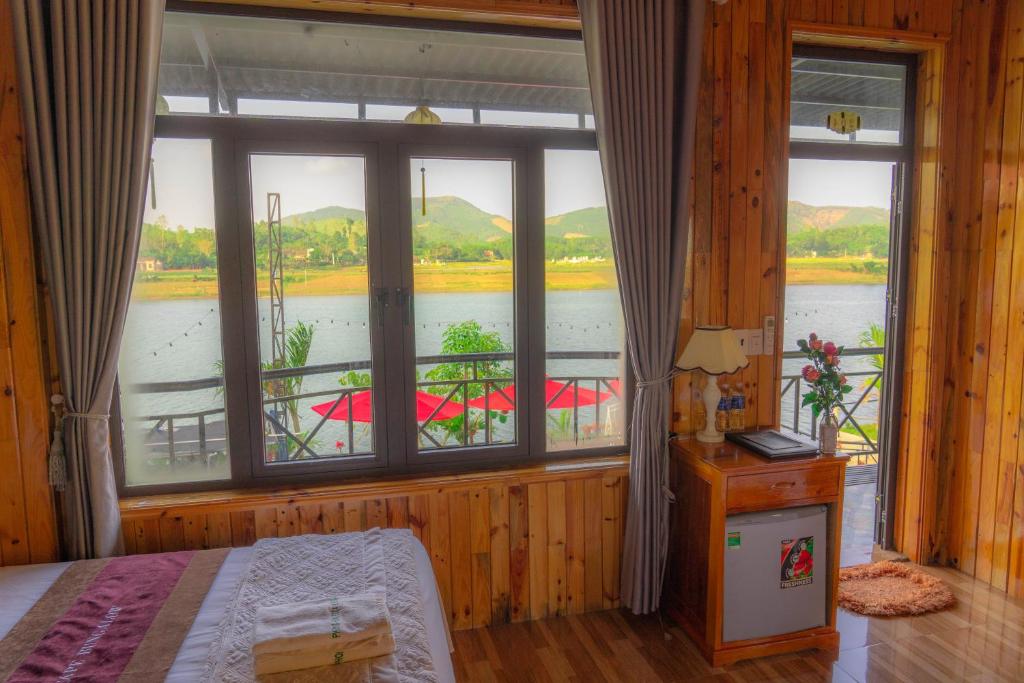 a bedroom with a large window with a view of a river at Phong Nha Escape Bungalow in Phong Nha