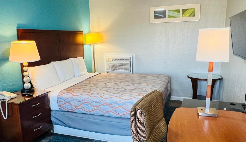 une chambre d'hôtel avec un lit et une table avec deux lampes dans l'établissement Relax Inn Lawton, à Lawton