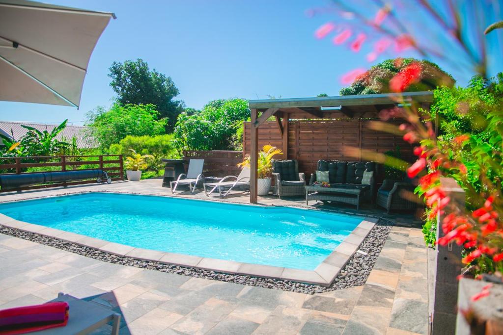 a swimming pool in a backyard with chairs and a gazebo at Villa Le Colonial Zen - T4 à 5 mn Aéroport in Sainte-Marie