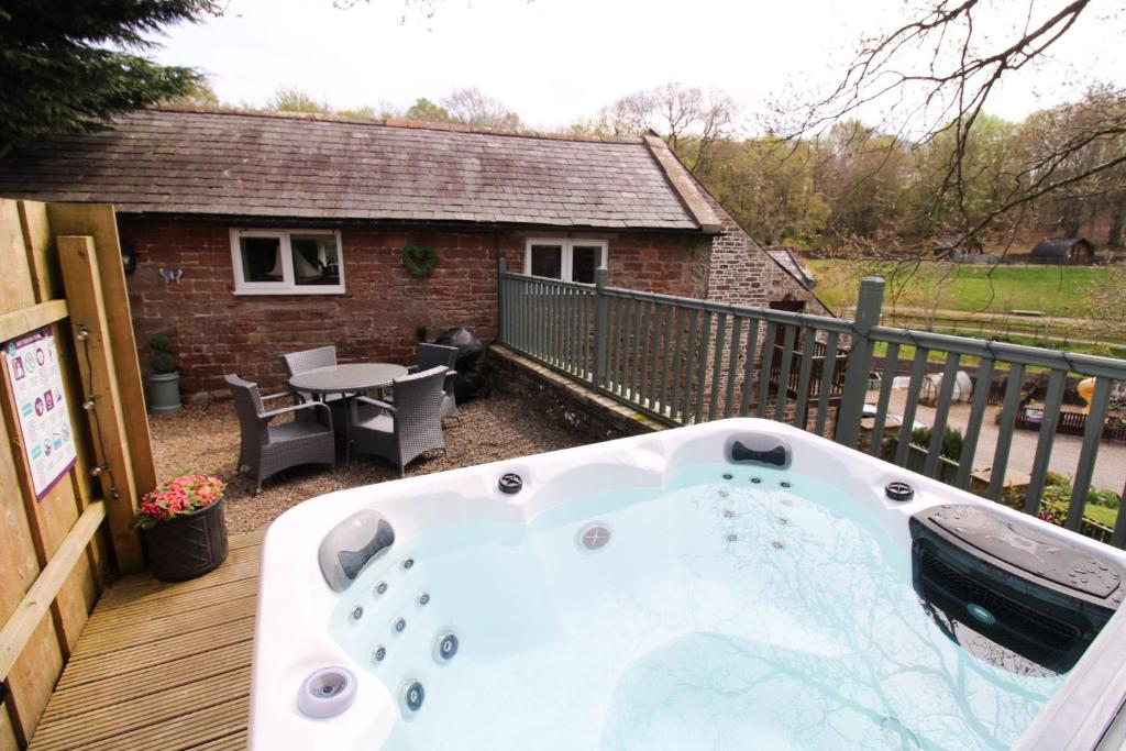 a jacuzzi tub on the deck of a house at Mill House Cottage, Fishing Park, Brampton, Nr Carlisle in Brampton