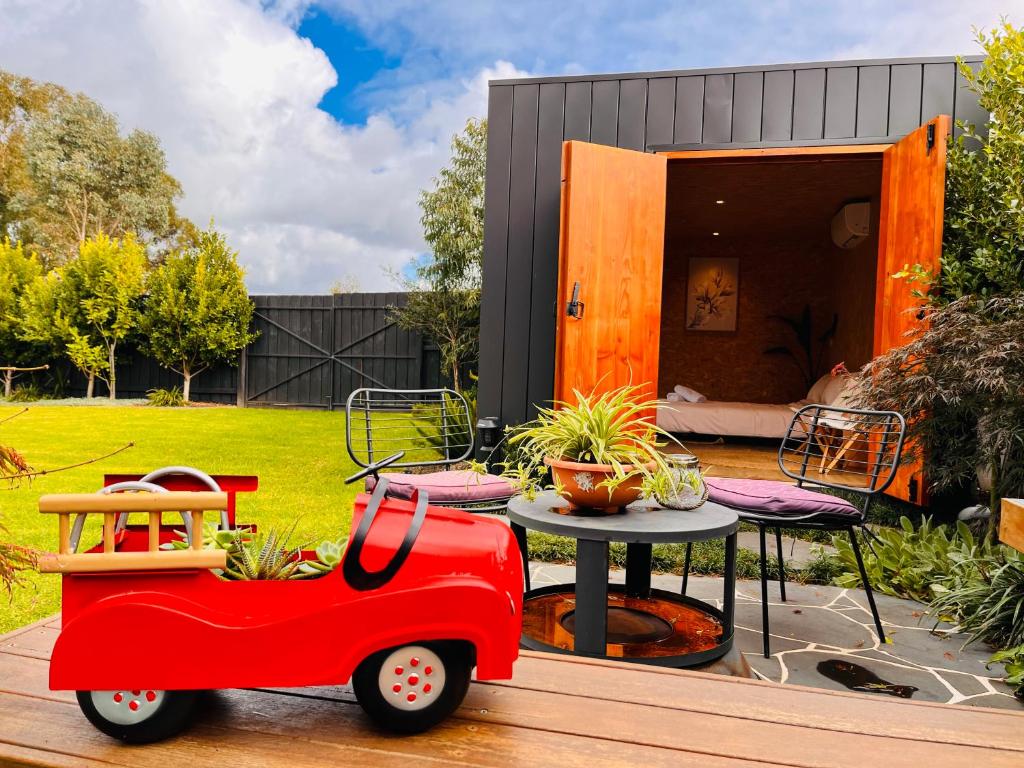 un coche de juguete rojo sentado en una cubierta junto a una mesa en holiday tiny house near park en Vermont South