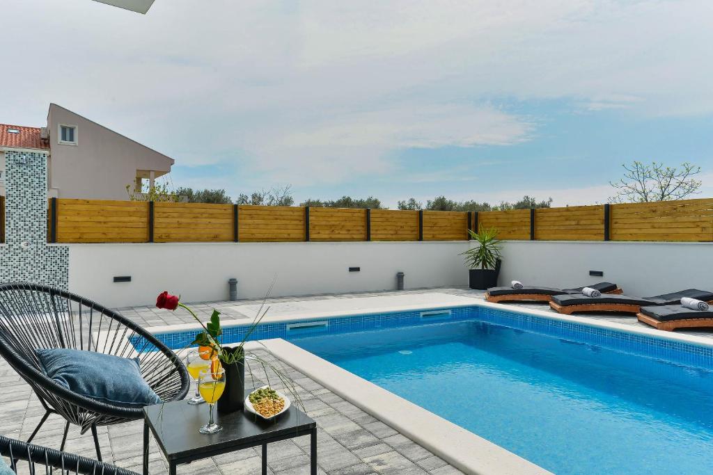 Una piscina con una mesa y una silla al lado de una piscina. en Villa Jomani, en Bibinje