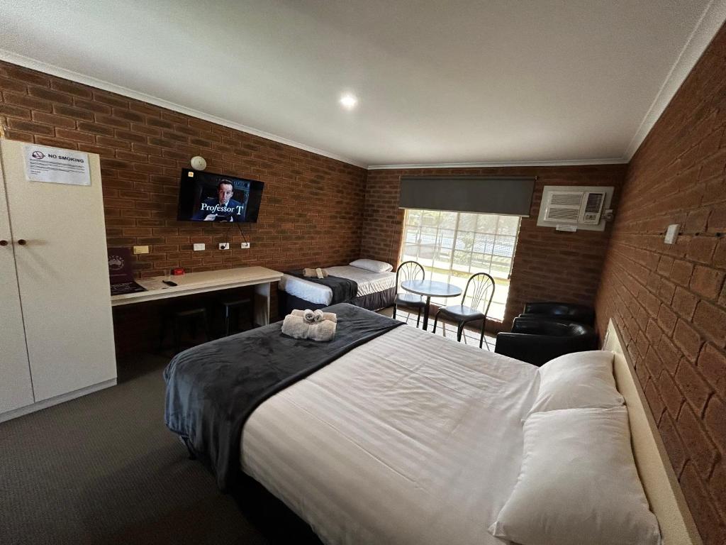 Habitación de hotel con cama y TV en una pared de ladrillo. en Balranald Colony Inn Motel en Balranald